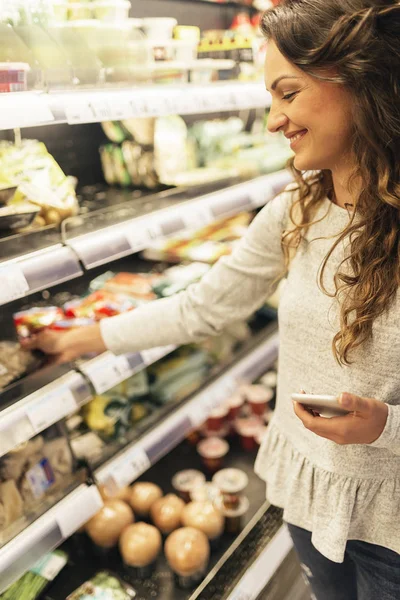 Красивая женщина выбирает еду в супермаркете . — стоковое фото