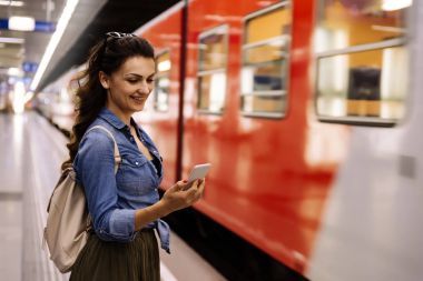 Cep telefonunu metro platformda kullanan güzel kadın.