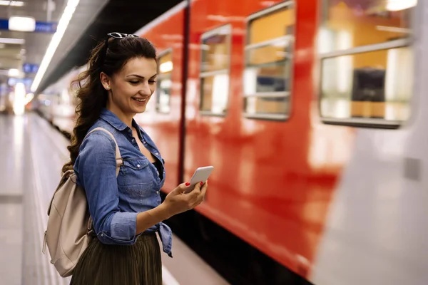 Hermosa mujer usando su teléfono celular en la plataforma del metro . — Foto de Stock