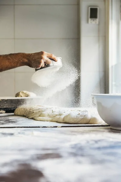 Baker hombre mano propagación de harina a la masa . —  Fotos de Stock