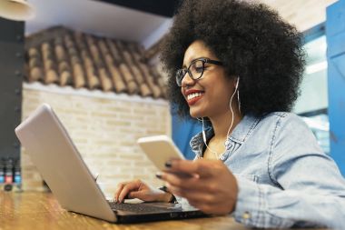 Cof içinde cep telefonu ve dizüstü bilgisayar kullanan güzel afro Amerikan kadın