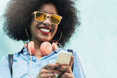 Beautiful afro american woman using mobile in the street.