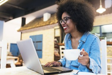 Cof içinde cep telefonu ve dizüstü bilgisayar kullanan güzel afro Amerikan kadın