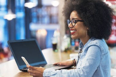 Cof içinde cep telefonu ve dizüstü bilgisayar kullanan güzel afro Amerikan kadın