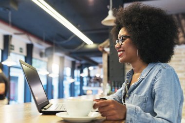 Cof içinde cep telefonu ve dizüstü bilgisayar kullanan güzel afro Amerikan kadın