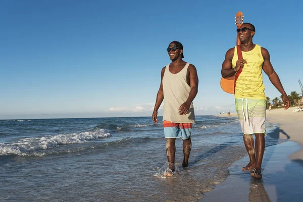 Dos amigos cubanos divirtiéndose en la playa con su guitarra . — Foto de Stock