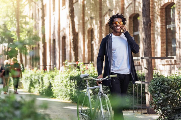 Afro jeune homme utilisant téléphone portable et vélo à engrenages fixes . — Photo