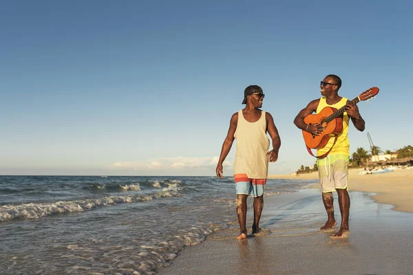 Zwei kubanische Freunde amüsieren sich am Strand mit seiner Gitarre. — Stockfoto
