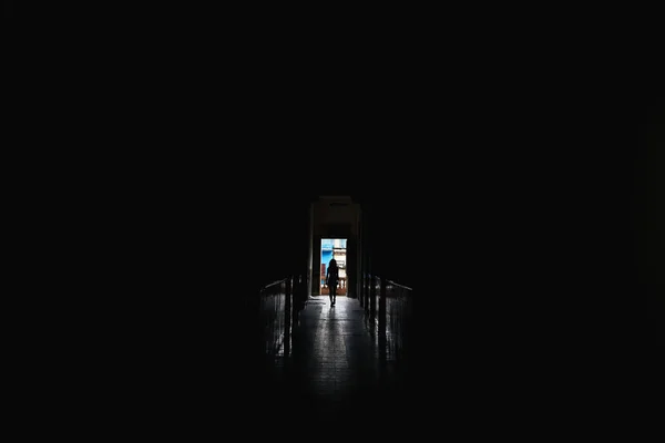 Kobieta chodząca samotnie w ciemnej sali. Koncepcja sylwetki. — Zdjęcie stockowe