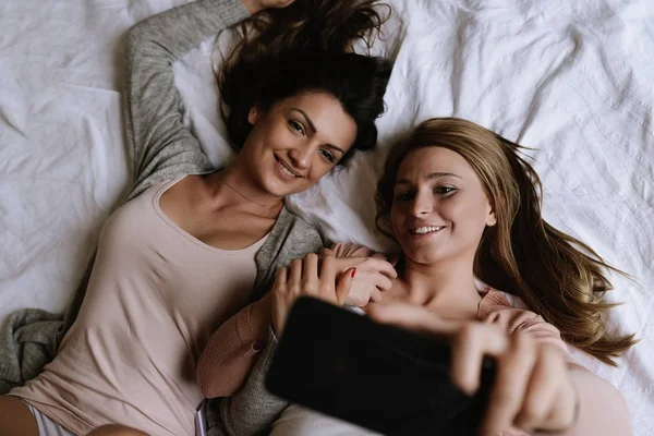 Gorgeous friends taking a selfie in the bedroom.