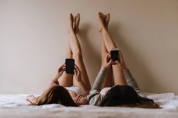 Gyönyörű barátok használ a mobil, a hálószobában. — Stock Fotó