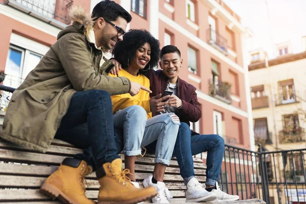 Grupo de amigos felizes usando o celular na rua . — Fotografia de Stock