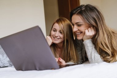 Muhteşem arkadaşlar yatak odasında dizüstü bilgisayar kullanarak.