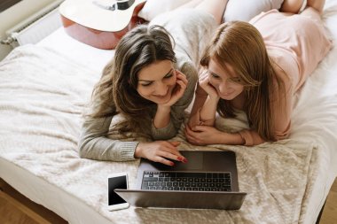 Muhteşem arkadaşlar yatak odasında dizüstü bilgisayar kullanarak