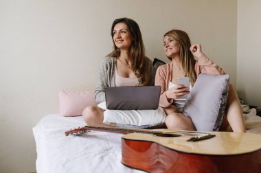 Muhteşem arkadaşlar laptop ve cep yatak odasında kullanarak.