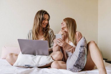 Muhteşem arkadaşlar laptop ve cep yatak odasında kullanarak.