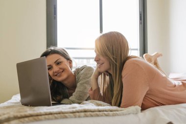 Muhteşem arkadaşlar yatak odasında dizüstü bilgisayar kullanarak.