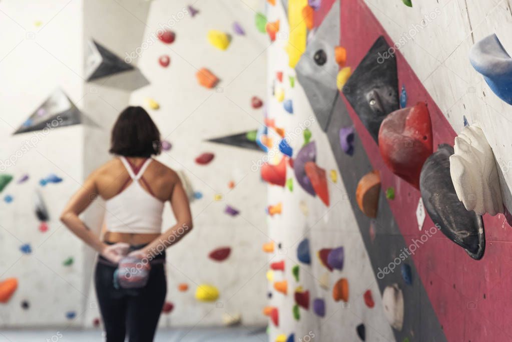 Woman ready for practice rock climbing on artificial wall indoors.