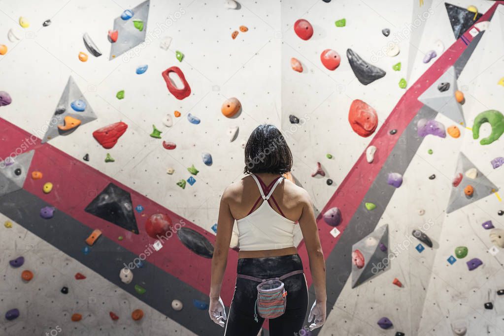 Unrecognizable woman ready for practice rock climbing on artificial wall indoors.