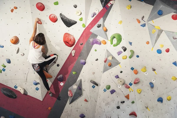 Egy nő, aki sziklát mászik a mesterséges falon. Aktív életmód és sziklaképződés. — Stock Fotó