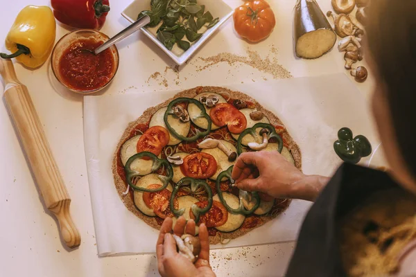 Женщина добавляет здоровые ингредиенты в пиццу . — стоковое фото