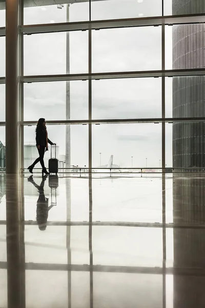 Nelze rozpoznat žena chůze s kufrem na letišti. — Stock fotografie
