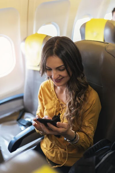 Belle femme utilisant le mobile à l'intérieur de la cabine de l'avion . — Photo