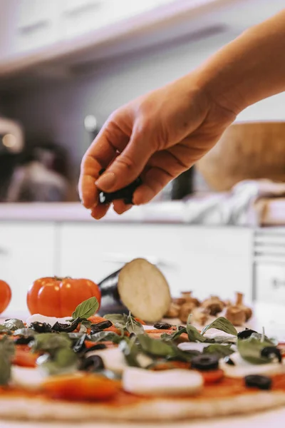 Donna che aggiunge ingredienti sani alla pizza . — Foto Stock