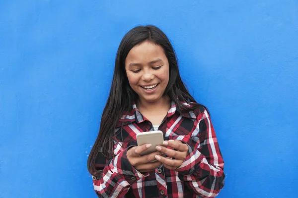 Porträt eines süßen Latino-Mädchens mit dem Handy auf der Straße. — Stockfoto