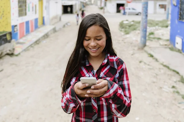 貧民街で携帯電話を使用してかわいいラテン系少女の肖像画. — ストック写真