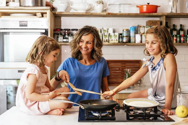 Irmãzinhas cozinhando com sua mãe na cozinha . — Fotografia de Stock