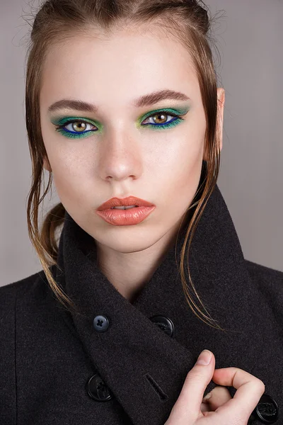 Menina bonita com maquiagem brilhante, pele perfeita e penteado como uma trança. Imagem tirada no estúdio sobre um fundo cinzento — Fotografia de Stock