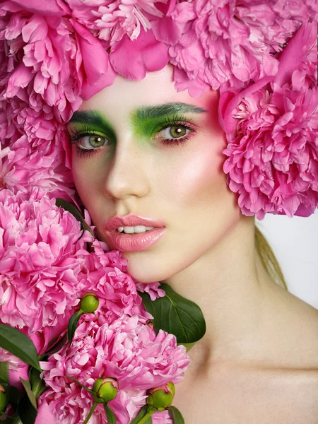 Mooi model meisje, met een glimlach en bloemen pioen in de buurt van het gezicht. Cosmetica, schoonheid en cosmetologie — Stockfoto