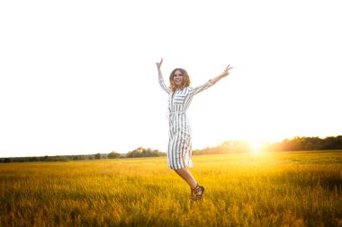 Happy girl jumping in a field at sunset
