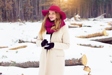 Genç, güzel ve şık Kızıl saçlı kız palto ve şapka termo Kupası tutar. Moda.