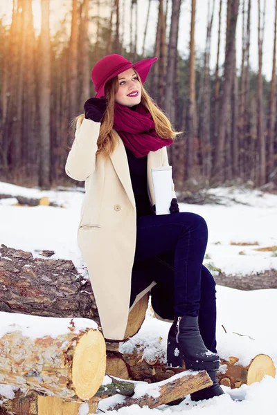 Giovane, bella ed elegante ragazza capelli rossi in cappotto e cappello mantiene una tazza termo. Moda . — Foto Stock