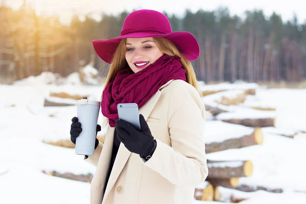 Elegante, giovane e bella ragazza che si fa un selfie con il suo telefono mantenendo una tazza termo. Moda . — Foto Stock