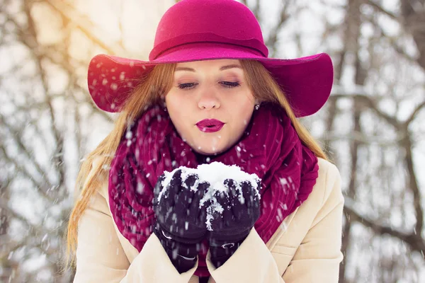 Bella, elegante e giovane ragazza, soffiando la neve dalle sue mani. Moda . — Foto Stock