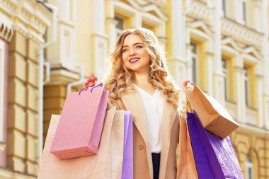 Shoppings ile şık, güzel sarı saçlı gülümseyen kız portresi. Mutlu alışveriş.