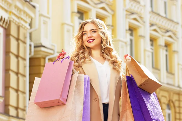 Shoppings ile şık, güzel sarı saçlı gülümseyen kız portresi. Mutlu alışveriş.
