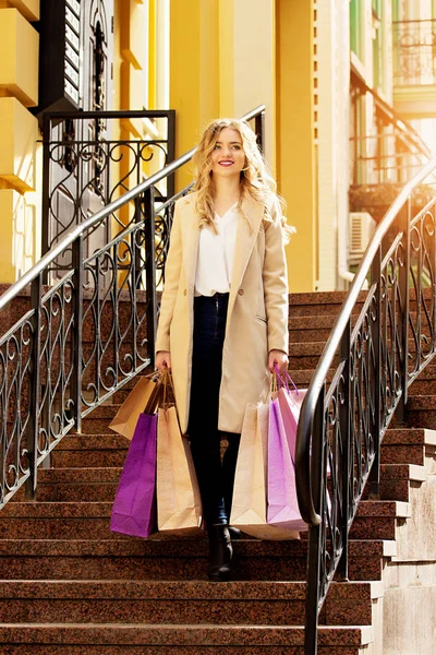 Menina sorrindo cabelo loiro elegante, bonito com compras. Compras felizes . — Fotografia de Stock