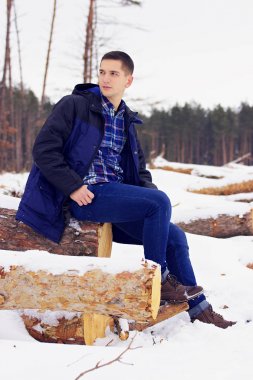 Orman ormanda oturan ceketli yakışıklı, şık ve genç adamı. Erken Bahar güneşli bir gün. Erkek moda.