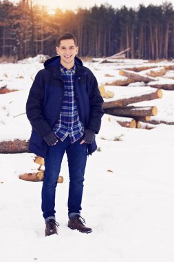 Yakışıklı, şık ve gülümseyen genç adam ceket ayakta ormanın içinde. Erken Bahar güneşli bir gün. Erkek moda.