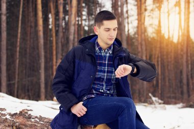 Ceketli yakışıklı, şık ve genç adamı onun saatler görünüyor. Erken Bahar güneşli bir gün. Erkek moda.