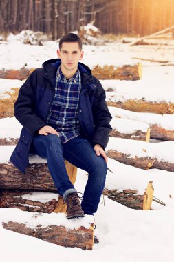 Yakışıklı, şık ve genç adam ormandan oturan ceket ve orman. Erken Bahar güneşli bir gün. Erkek moda.