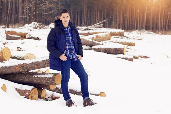 Knappe, stijlvolle en jonge man in jas zittend op de bossen in het forest. Vroege voorjaar, zonnige dag. Mannen mode. — Stockfoto