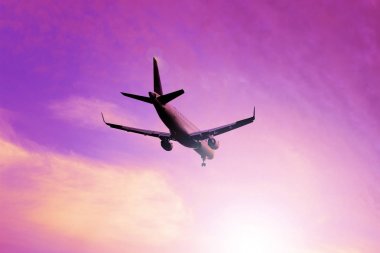 Gündoğumu gökyüzünde bulutlar üzerinden uçan bir uçak. Jet uçakları.
