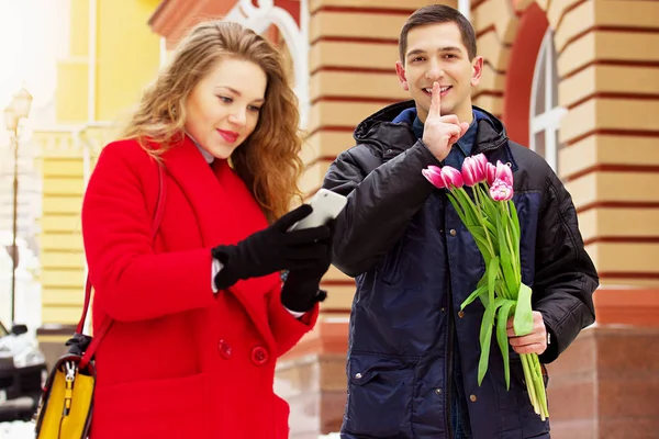 Romantikus dátum. Ember, virágokkal, felkészülés a váratlan meglepetés a barátnője. Gyönyörű fiatal pár gyaloglás együtt a város utcáin. Tavaszi. — Stock Fotó