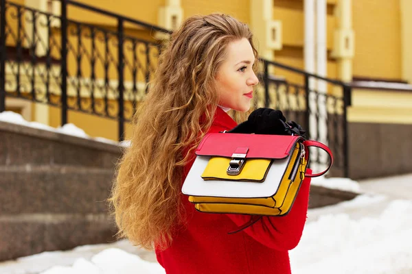 Joven, hermosa y elegante chica de pelo rubio con abrigo rojo y llevando un bolso en la espalda. Moda para mujer . — Foto de Stock