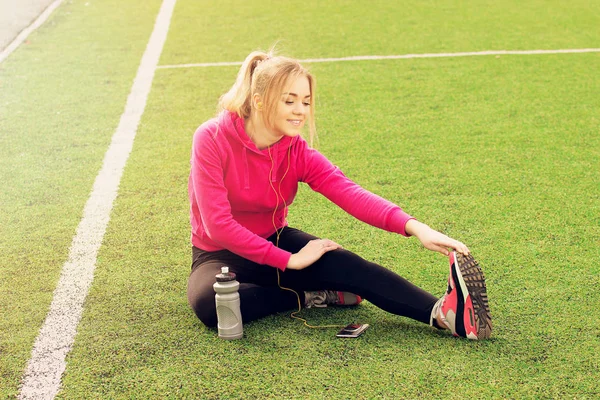 Fiatal gyönyörű szőke haja fitness lány csinál, stretching a stadion. Nyári sport tevékenység. — Stock Fotó